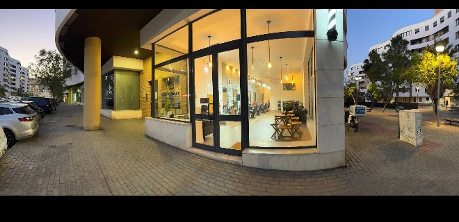 Fachada de vidro da barbearia ao entardecer com interior visível